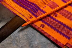 Close-up of a colorful handwoven Mexican textile in orange and purple hues.